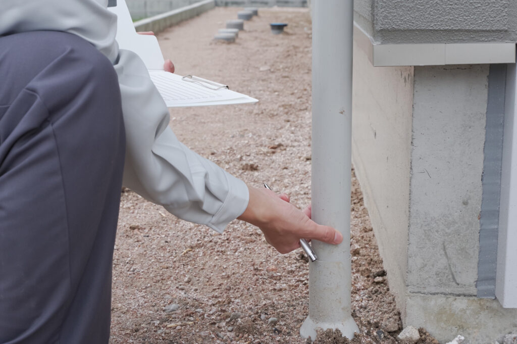 住宅の雨どいを点検・施工する作業の様子